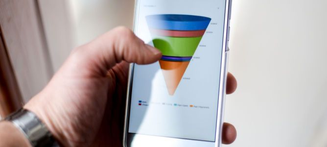 Male hand holding a smart phone showing a marketing sales funnel