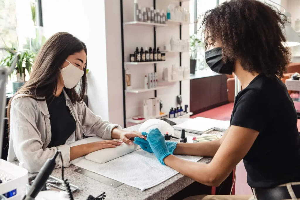 A manicurist is applying nail polish to a client 